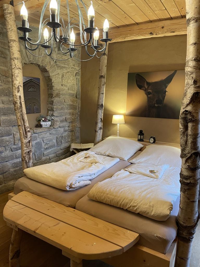 Doppelbett aus Birkenstämmen mit Natursteinwand und Lehmputz in der besonderen Ferienwohnung im Harz - Hester Street in Earls Lane
