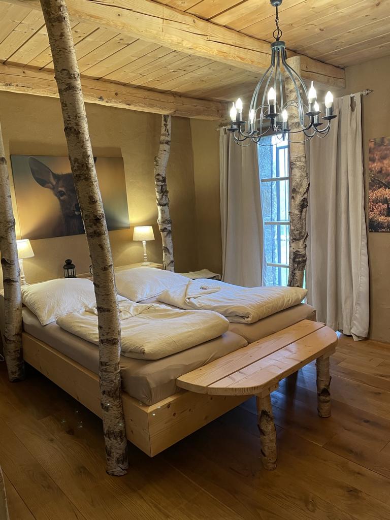 Doppelbett aus Birkenstämmen mit Natursteinwand und Lehmputz in der außergewöhnlichen Ferienwohnung im Harz - Hester Street in Earls Lane