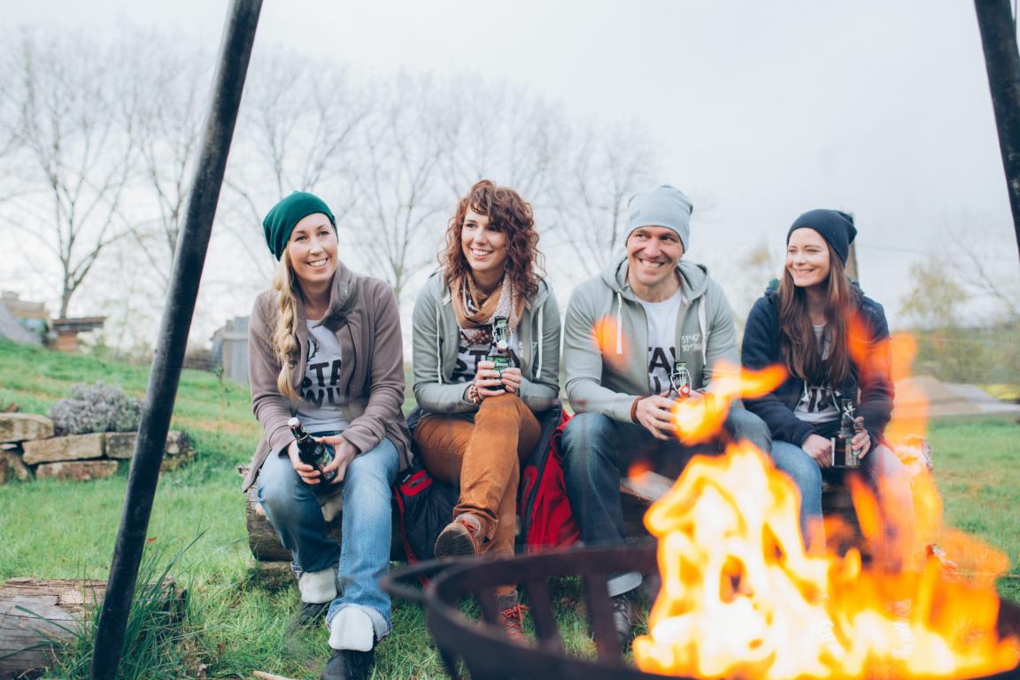 4 Menschen sitzen vor einem Lagerfeuer in Earls Lane im Harz - Modeshooting Harzkind